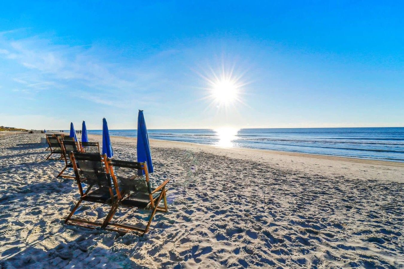 A beach with sun umbrellas and lounge chairs.