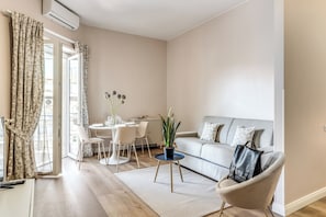 Ein modernes Wohnzimmer mit einer Couch, einem Couchtisch, einem Esstisch mit Stühlen und einer Topfpflanze.