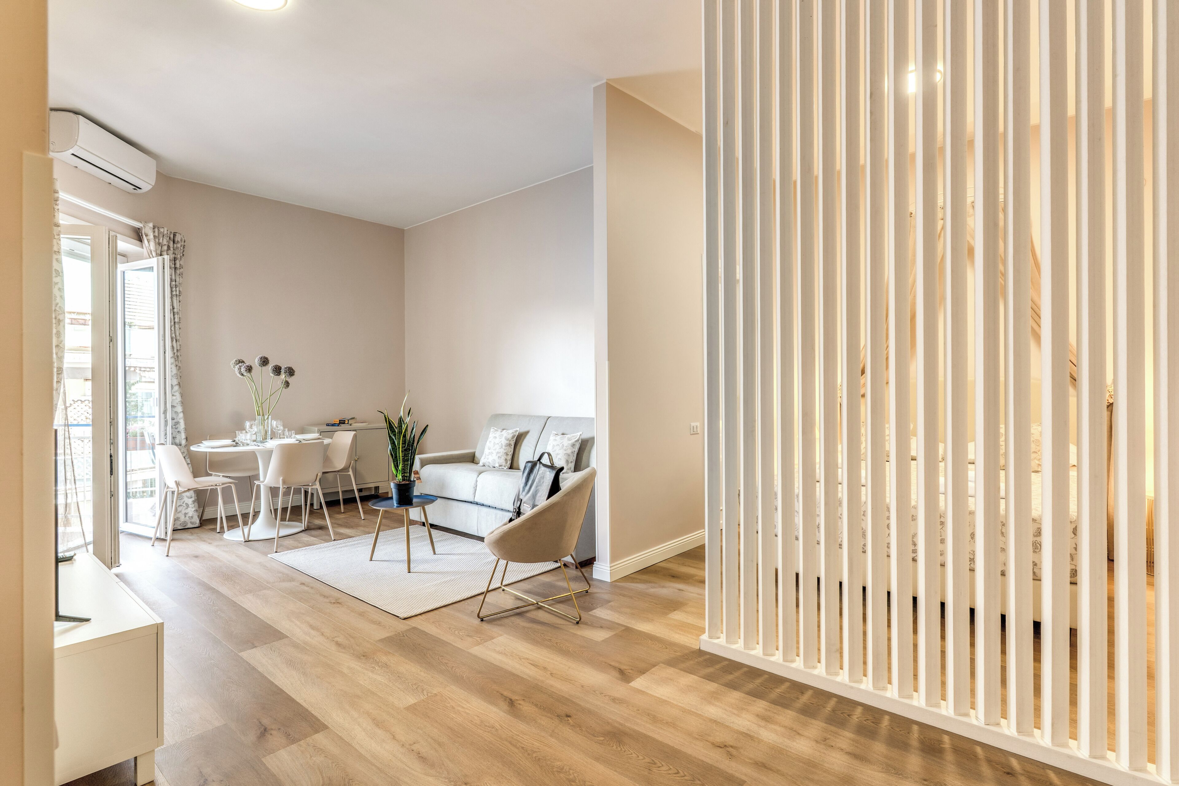 Un salon moderne comprenant un canapé, des fauteuils, une table à manger et une cloison blanche.
