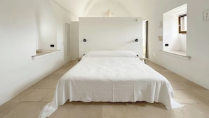 Ein Schlafzimmer mit einem großen Bett, einer Pendelleuchte und einem Fenster mit Blick.