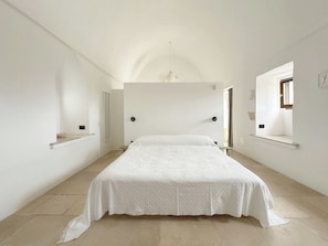 Ein Schlafzimmer mit einem großen Bett, einer Pendelleuchte und einem Fenster mit Blick.