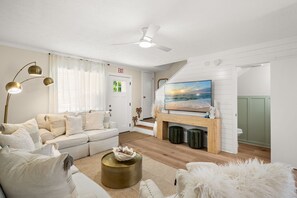 Ein Wohnzimmer mit einer Couch, einem Couchtisch, einem Kamin und einem Fernseher.