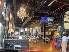 Un intérieur comprenant un espace bar, des tables, des chaises et un lustre.