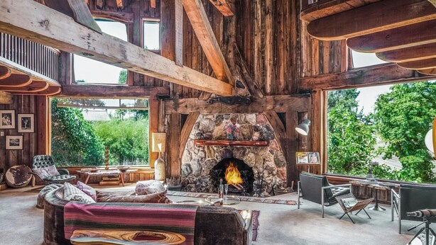 Un interior rústico con chimenea de piedra, vigas de madera y una zona de estar acogedora.