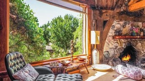 Una habitación acogedora con chimenea, un sillón cómodo, una mesa de comedor y vistas al exterior.