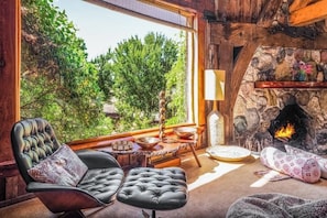 A cozy room with a fireplace, a comfortable chair, a dining table, and a view of greenery outside. - Luxury Wine Country Estate Near Downtown/Wineries (Paso Robles)