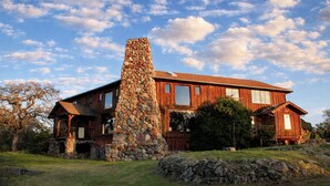 Una casa de madera con chimenea de piedra, ventanas grandes y cimientos de piedra.