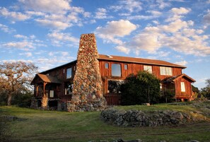 A wooden house with a stone chimney, large windows, and a stone foundation. - Luxury Wine Country Estate Near Downtown/Wineries (Paso Robles)