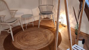 A room with a wooden ceiling, a white chair, a round rug, and a wooden hanger rack. - Bed & Breakfast Chez Mon Reve (Éguzon-Chantôme)