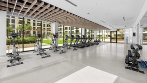 Et moderne fitnesscenter med forskellig træningsudstyr, store vinduer og et rent, rummeligt indre.