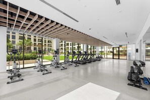 A modern gym with various exercise equipment, large windows, and a clean, spacious interior. - Free Housekeeping Visits During Your Stay - StayShort - Beautiful Dubai Hills 1BR Apartment that Sleeps Up to 4 (Dubai Hills Estate)