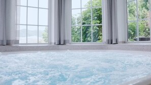 Un jacuzzi con vista a la vegetación a través de amplias ventanas.