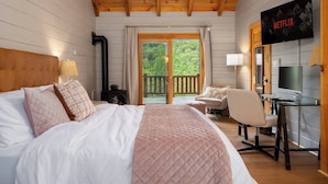 A hotel room with a bed, a desk, a chair, a TV, and a balcony with a view of greenery. - Postcard-worthy views, 4 Decks, Jetted Tub (Burnsville)