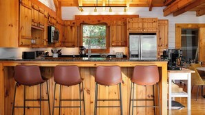 A wooden kitchen with a central island, bar stools, and a refrigerator. - Postcard-worthy views, 4 Decks, Jetted Tub (Burnsville)