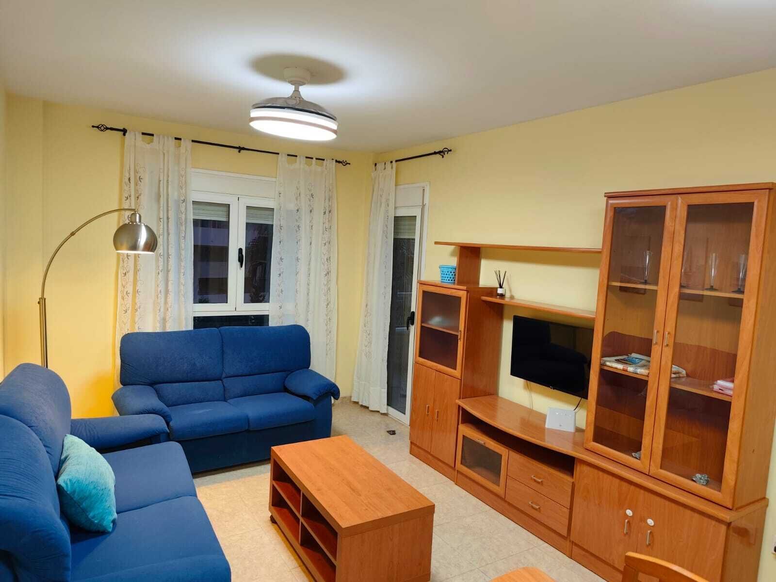 Un salon avec un canapé bleu, un meuble en bois et un téléviseur.