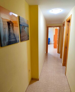 A hallway with yellow walls, a tiled floor, and wooden doors. - Apartment Urb. Roquetas de Mar. Air conditioning. Close to the beach. (Roquetas de Mar)