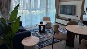 Ein modernes Wohnzimmer mit großem Fenster, Flachbildfernseher, einer Couch, einem Couchtisch und einem Essbereich.