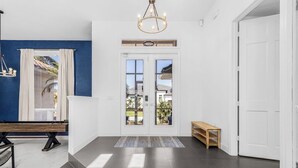A modern interior with a double door entrance, a bench, a small table, and a chandelier. - Peaceful Newly Renovated Canal Home in Punta Gorda (Punta Gorda)