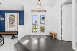 A modern interior with a double door entrance, a bench, a small table, and a chandelier. - Peaceful Newly Renovated Canal Home in Punta Gorda (Punta Gorda)