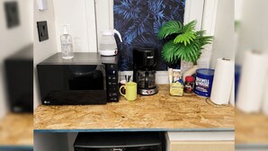 Cozinha com micro-ondas, cafeteira e um vaso de planta.