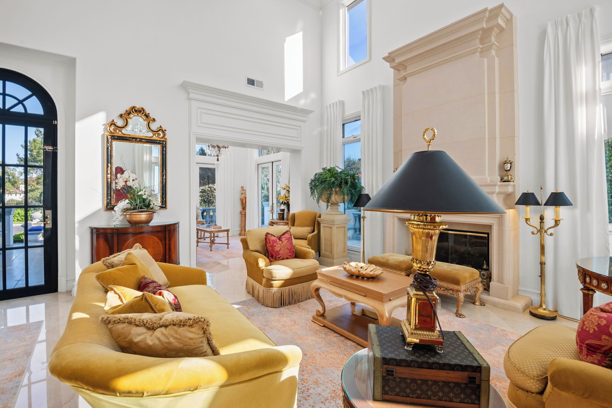 A spacious living room with a fireplace, elegant furniture, and a large mirror.