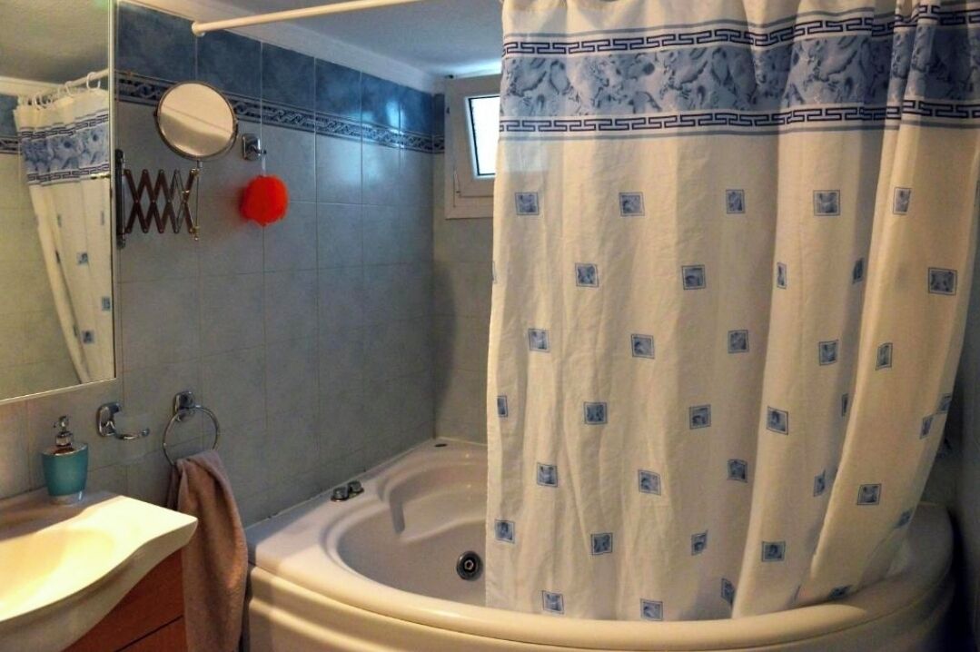 Une salle de bain avec une baignoire, un miroir, un porte-serviettes et un rideau de douche.