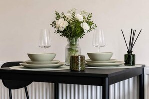 Ein Esstisch mit zwei Schüsseln, einer Blumenvase und einem Reed-Diffuser.