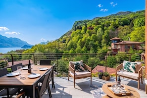 A terrace with a table set for dining, overlooking a mountainous landscape and a lake. - Magical Menaggio Vista, Menaggio, Italy (Menaggio)