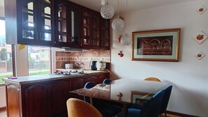 Eine Küche mit Holzausstattung, einem Esstisch mit Stühlen, einer Kaffeemaschine und einem gerahmten Bild an der Wand.