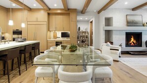 Eine moderne Küche mit Holzschränken, einem Glastisch und einem Kamin.