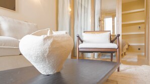 Una sala de estar moderna con un sofá, una silla, una mesa y un jarrón blanco grande.