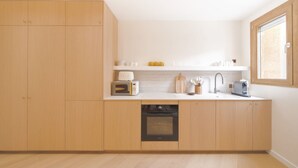 Una cocina moderna con armarios de madera, horno empotrado, microondas y ventana.