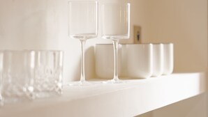 Dos vasos transparentes sobre un estante blanco.