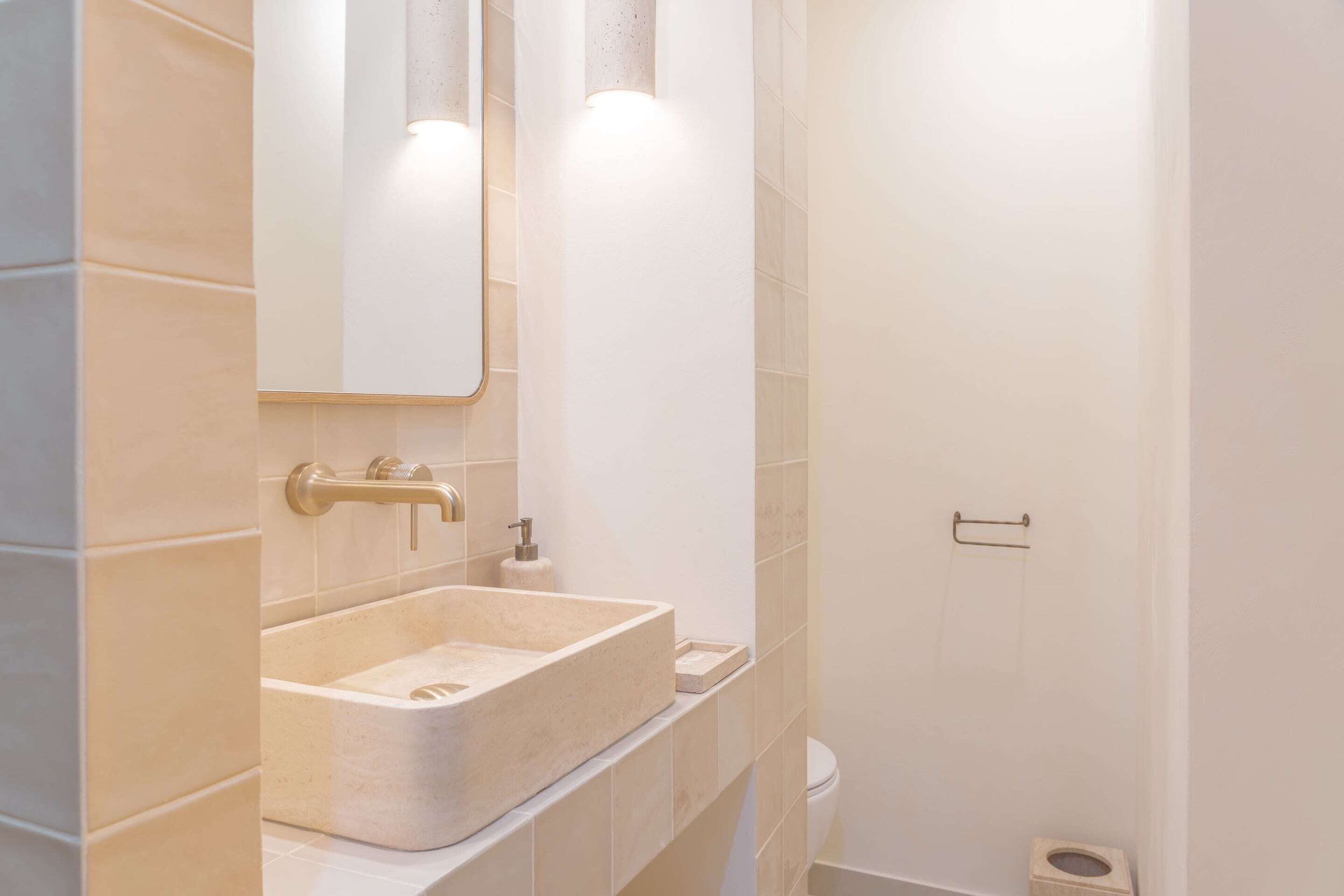 Un baño con un lavamanos rectangular, un inodoro y un espejo.
