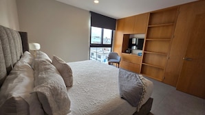 Quarto com cama, cadeira, televisão e guarda-roupa.