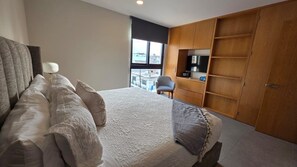 Ein Schlafzimmer mit einem Bett, einem Sessel, einem Fernseher und einem Kleiderschrank.
