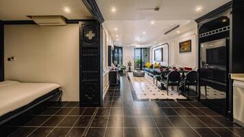 A modern hotel room with a bed, a dining area, and a kitchen.