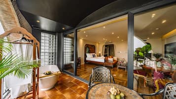 Een modern interieur met een eethoek, een slaapkamer met een groot bed en een bank, en uitzicht door een glazen deur.
