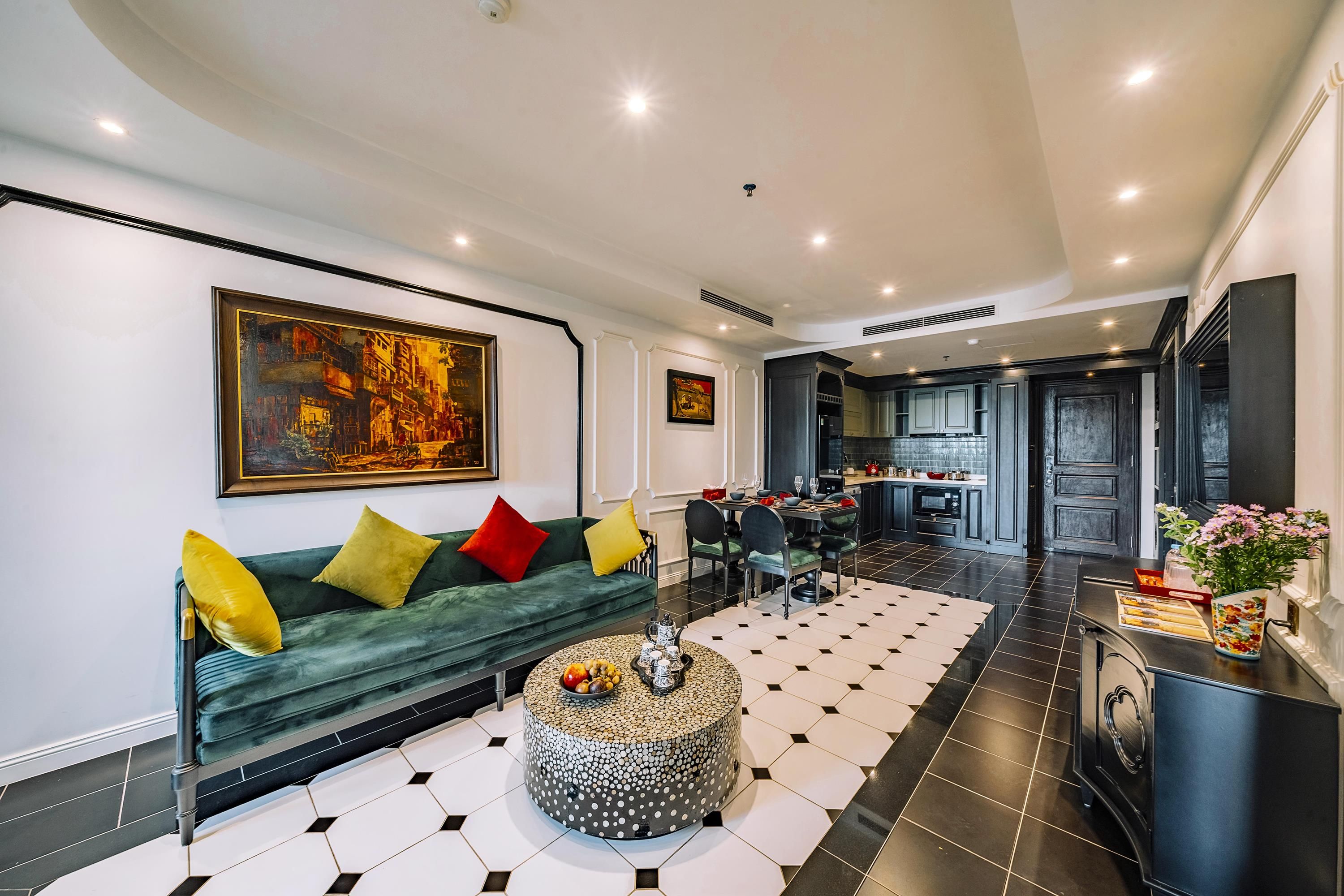 A modern living room with a green sofa, a round coffee table, and a dining area with a black and white tiled floor.
