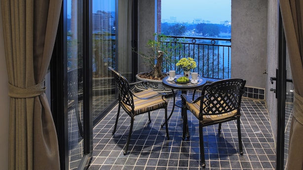 A balcony with a table, chairs, and a potted plant.