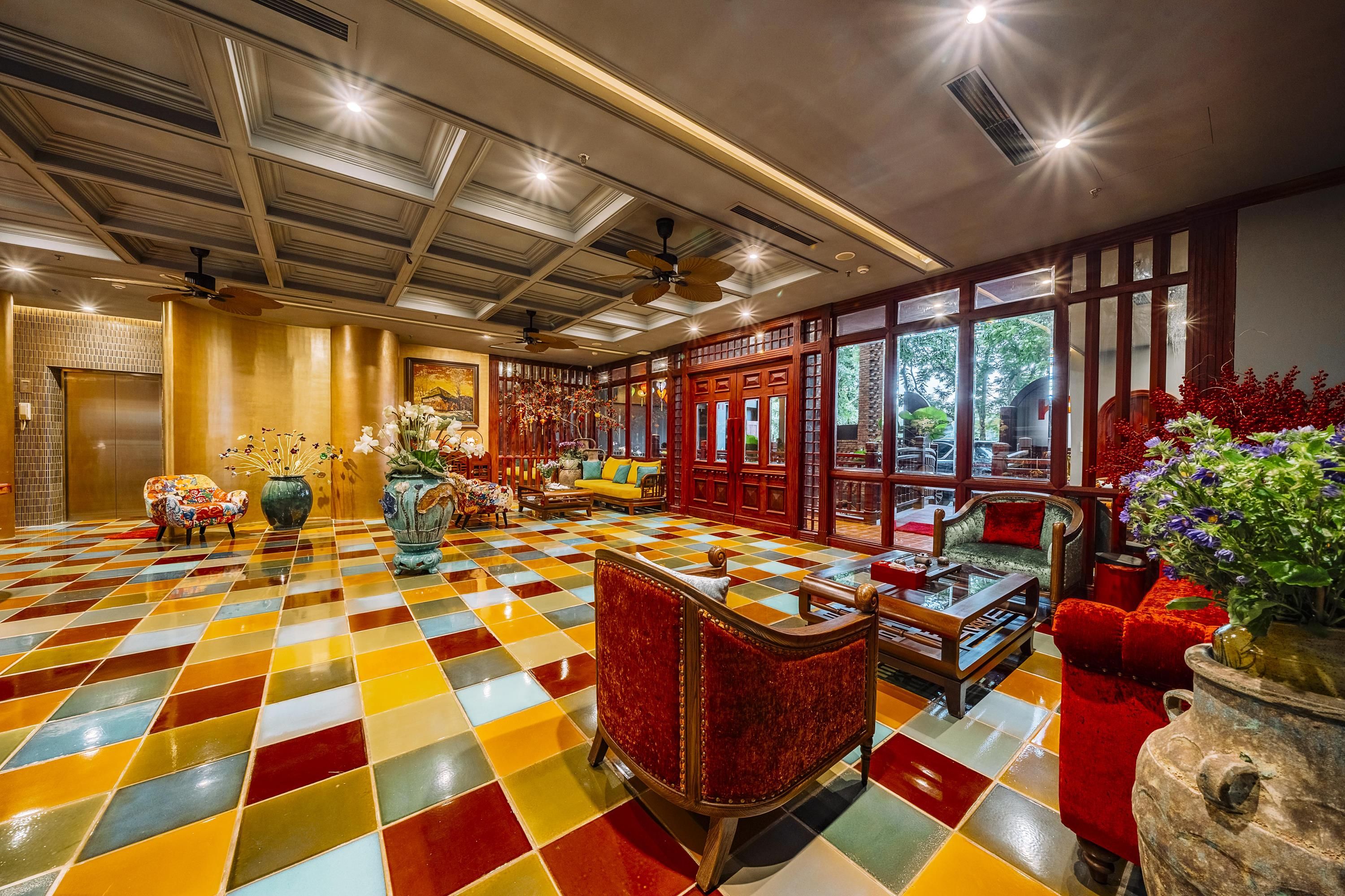 A hotel lobby with a checkered floor, wooden furniture, and large windows.