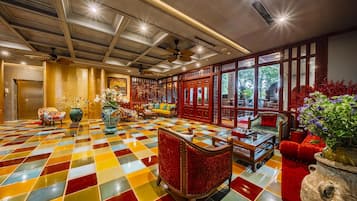 A hotel lobby with a checkered floor, wooden furniture, and large windows.