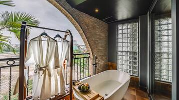 A modern bathroom with a freestanding bathtub, a glass shower enclosure, and a view of the cityscape.