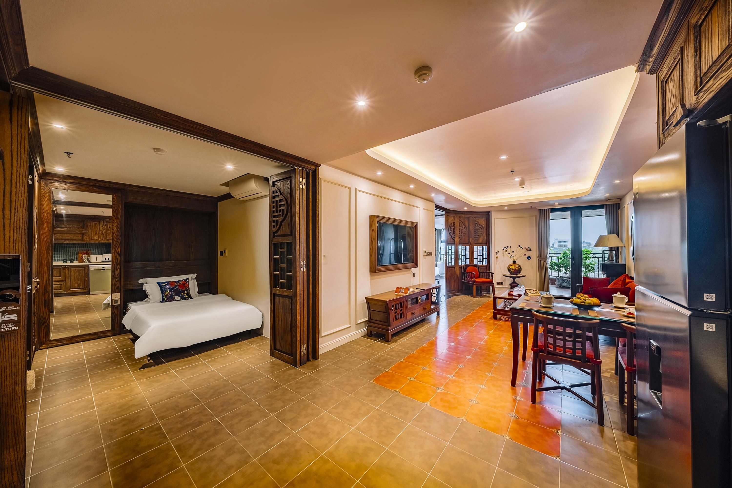 A spacious hotel room with a large bed, a dining area, and a kitchen.