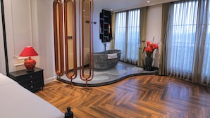 A modern bathroom with a stone bathtub, a red lamp, and a large window with curtains.