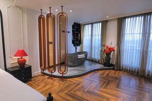 Un baño moderno con una bañera de piedra, una lámpara roja y un amplio ventanal con cortinas.