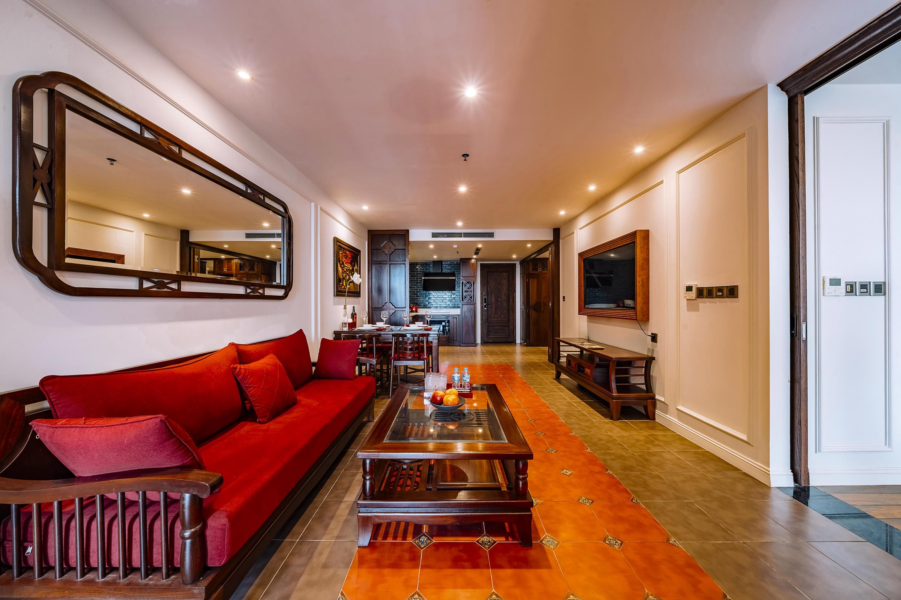 A modern living room with a red sofa, a coffee table, and a large mirror.
