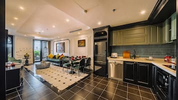 A modern kitchen with black cabinets, a built-in oven, and a dining area with a round table and chairs.