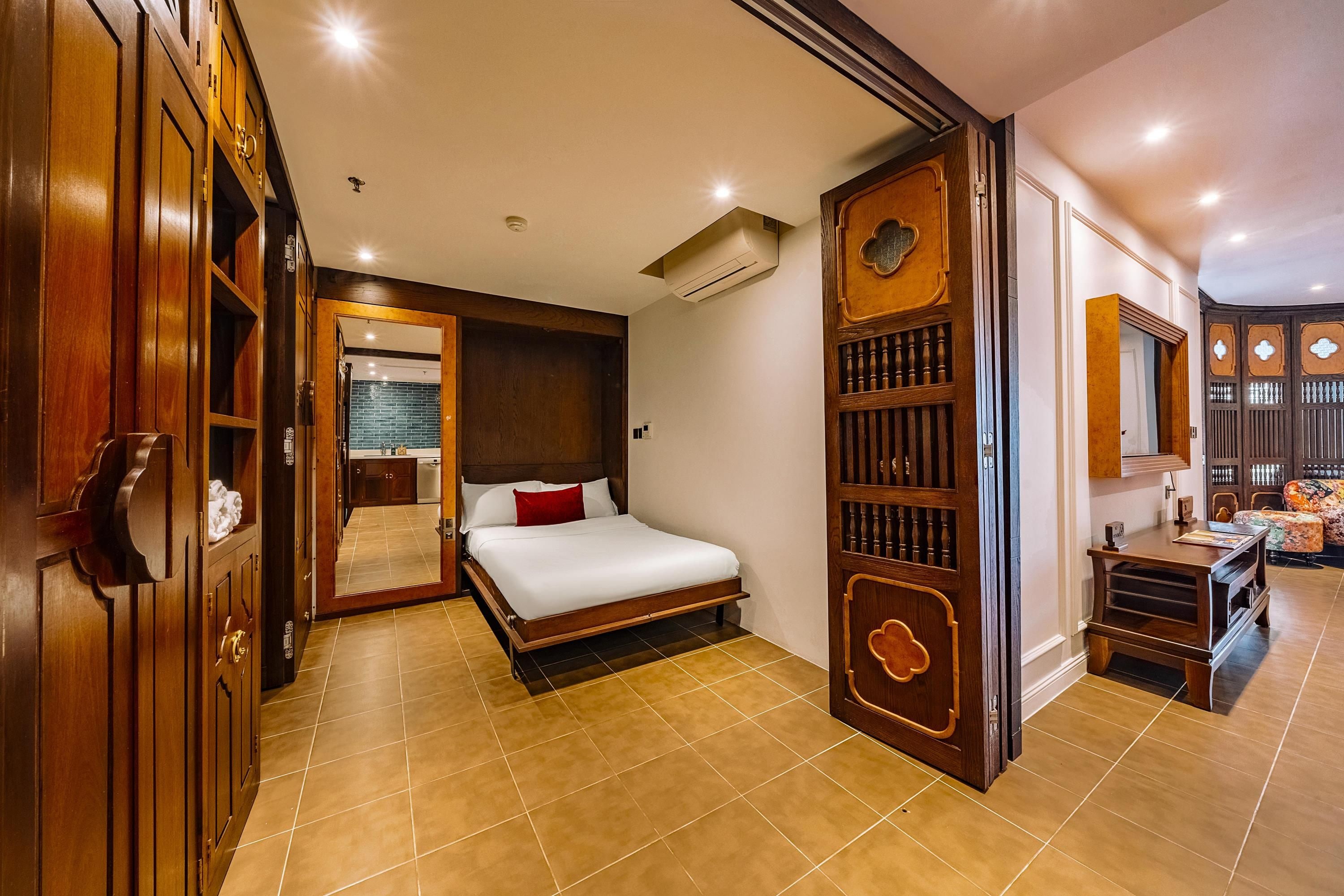 A hotel room with a bed, a wardrobe, a bathroom, and a seating area.