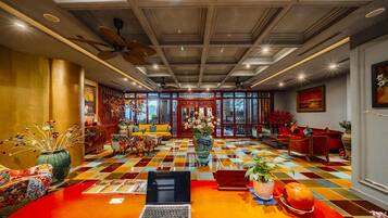 A spacious room with a checkered floor, a laptop on a table, and a ceiling fan.